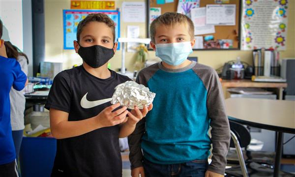 Students hold aluminum boats